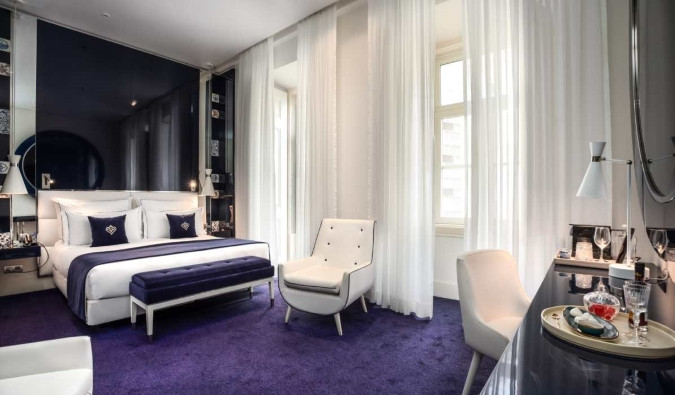 Luxurious hotel suite in Lisbon with blue rugs, a sleek desk, and a large bed.