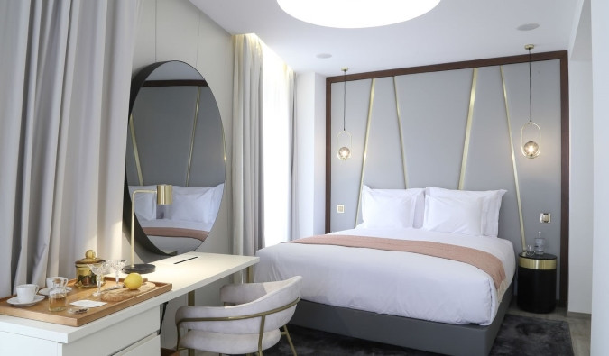 Modern hotel room with a round mirror, a writing desk, and a bed with hanging lights in Lisbon.