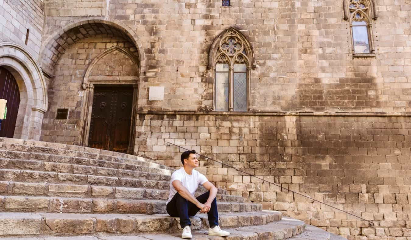 Nomadic Matt sitting and thinking on the steps in Barcelona, Spain, contemplating the future of travel blogging
