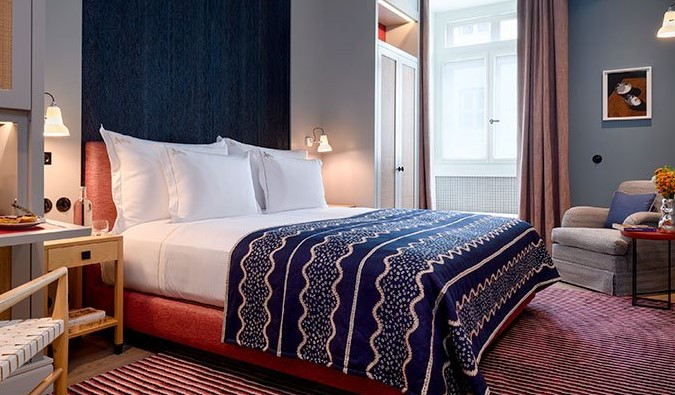 Stylish hotel room with blue walls, a magenta rug, and a king-sized bed in Lisbon.