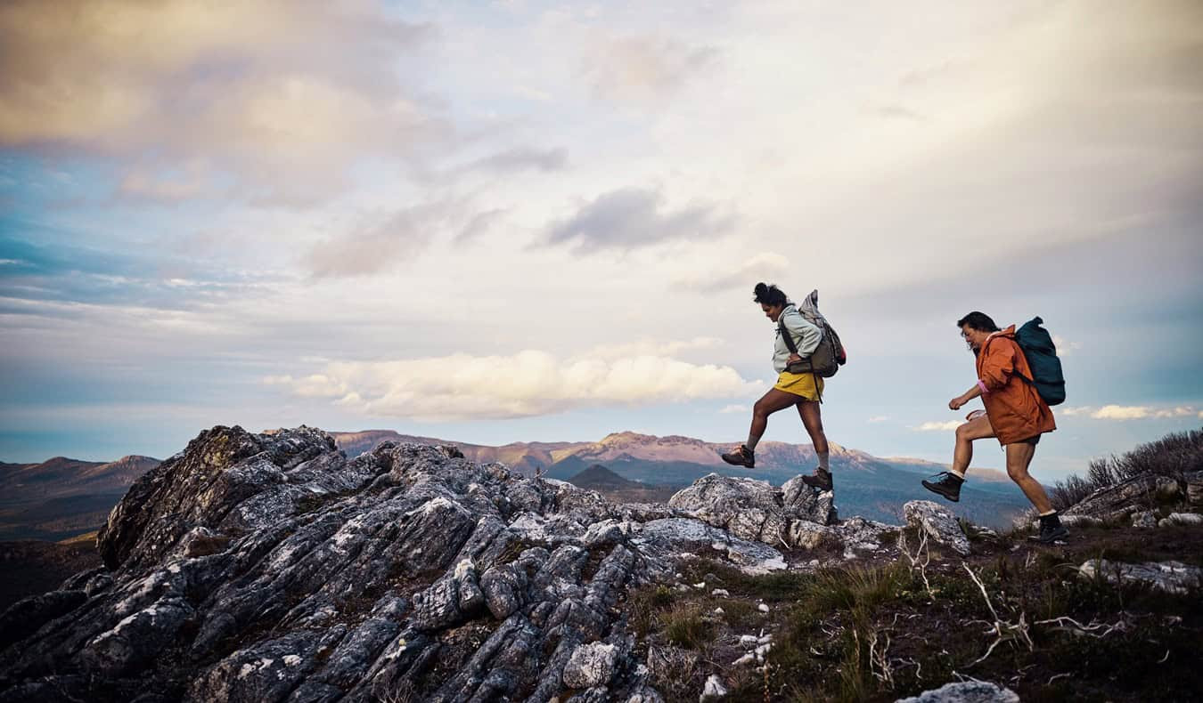 Two hikers with backpacks on a mountain trail.